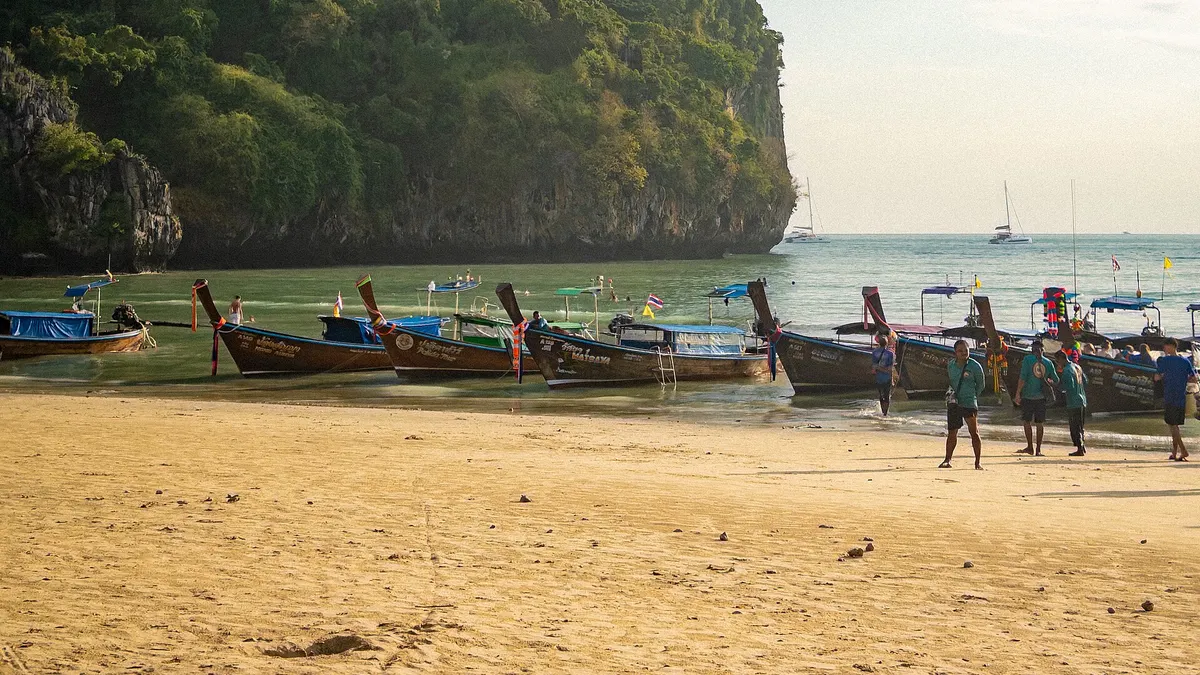 Longtail boats on Railay West beach below limestone cliffs